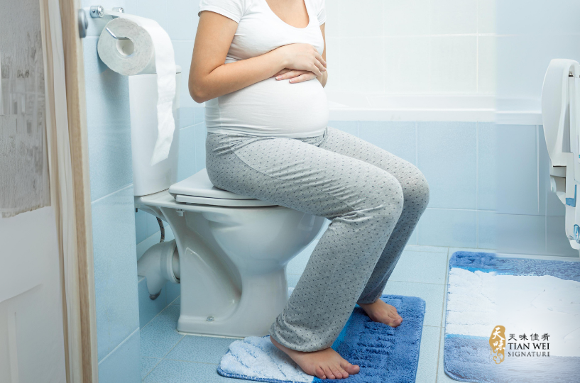 Pregnant woman sitting on the toilet.